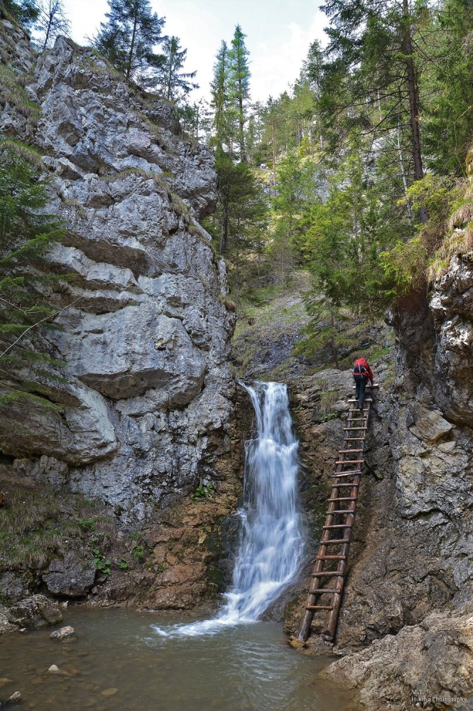 Turista lezúci po rebríku popri vodopáde v Kvačianskej doline