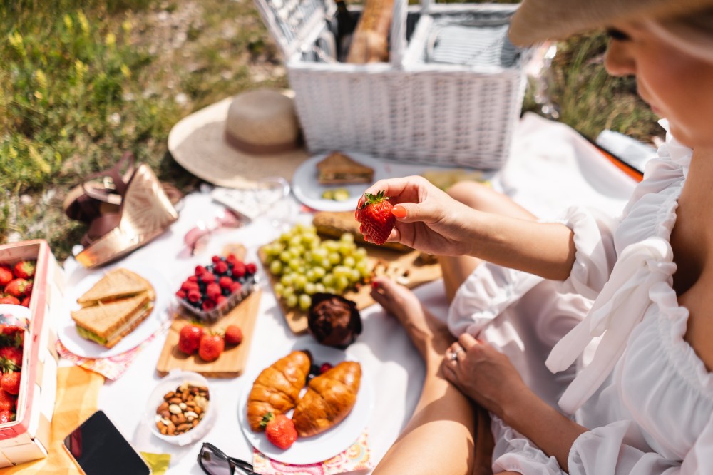 Žena ide jesť jahody a iné dobroty na pikniku vo vinici