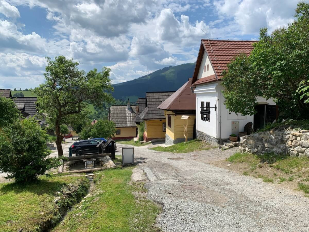 Biela a tri žlté pôvodné slovenské chalúpky pri dedinskej ceste.